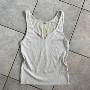 Vit ribbad linnetopp från Cotton On - Säljer en superfin vit ribbad linnetopp från Cotton On. Den är ärmlös och har en snygg v-ringad design. Perfekt för sommardagar eller som ett basplagg i garderoben. Storlek XS och i bra skick! skriv vid frågor💗