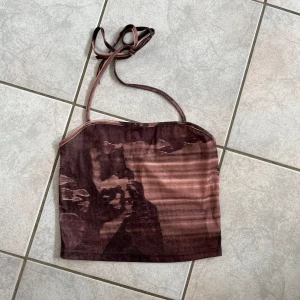 Brun mesh topp - Säljer en brun mesh topp med tunna axelband. Toppen har ett unikt mönster och är perfekt för en somrig look. Den är lätt och luftig, vilket gör den idealisk för varma dagar. skriv vid frågor💗