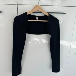 Bolero från Nelly  - Svart bolero från Nelly i ett stretchig material. Boleron är i stl L men är ganska liten i storleken. Passar mer M