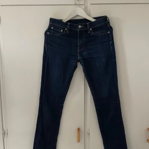 Mörkblå jeans från Levi's - Säljer ett par snygga mörkblå jeans från Levi's. De har en klassisk femficksdesign och är i en slim passform. Perfekta för både vardag och fest! Står w30 l32 men skulle säga att de sitter som en m/s de är raka i modellen och smått skinny