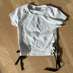 Ribbad tshirt med snörning - Ribbad vit T-shirt med snörning på sidorna. Helt oanvänd med prislappen kvar😇