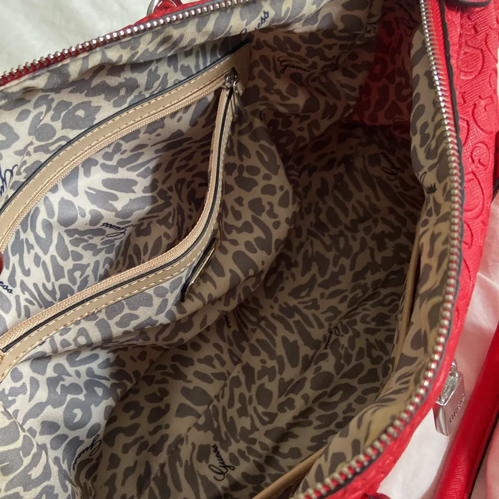 Röd väska från GUESS med leopard print på insidan. Använd av min syster för flera år sedan. Köptes ny! Allt finns fortfarande med, inga fläckar ingenting. Kom med bud. Laukut & Käsilaukut.