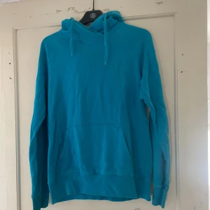Turkos hoodie - Säljer en snygg turkos hoodie i storlek 40. Den är perfekt för både höst och vår med sin mysiga känsla och känguruficka framtill. Huvan har dragsko för justering. Perfekt för en chill dag eller en promenad i parken!