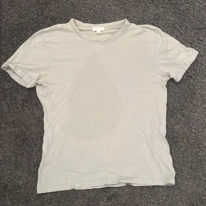 Grå t-shirt från COS - Säljer en stilren grå t-shirt från COS i storlek L. T-shirten är tillverkad i mjukt material och har en klassisk rund halsringning. Perfekt för en avslappnad look.