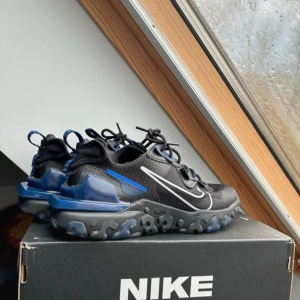 Nike sneakers med blå detaljer - Snygga Nike sneakers i svart med blå detaljer och vit swoosh. Skorna har en unik sula med mönster och snörning för bra passform. Perfekta för en sportig look.