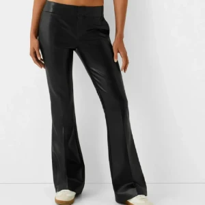 Svarta skinnbyxor - Snygga svarta skinnbyxor med bootcut-stil. De är  lågmidjade, avklippta och passar någon som är 160cm. 