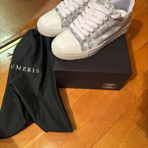  Numeris skor - Snygga grå sneakers från Numeris med ett unikt mönster. Skorna har vita snören och en vit sula som ger en fräsch look. Perfekta för en stilren vardagsstil. Använda endast 2  gånger. Ordenarie pris 2500kr