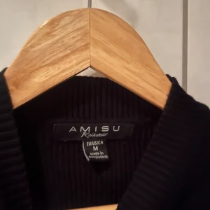 Svart ribbad tröja från Amisu - Säljer en stilren svart ribbad tröja från Amisu. Tröjan har långa ärmar med dekorativa knappar vid ärmsluten. . Passar bra till både jeans och kjol.