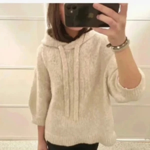 Beige stickad hoodie - Mysig beige stickad hoodie med trekvartsärm och luva. Perfekt för kyliga dagar. Den har en avslappnad passform och ribbade kanter. En stilren och bekväm tröja för vardagsbruk.