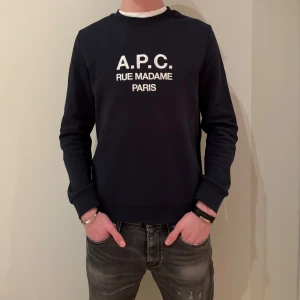 Mörkblå sweatshirt från A.P.C. - Stilren mörkblå sweatshirt från A.P.C. Mycket bra skick då den bara är använd ett fåtal gånger. Tröjan är köpt på NK för 2500kr, mitt pris 800kr. Storleken är S men passar även de som gränsar till medium. Tveka inte på att höra av dig kring frågor om tröjan! 