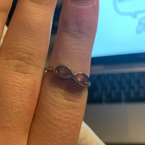 Silverfärgad ring med oändlighetssymbol - Elegant silverfärgad ring med en stilren oändlighetssymbol. Perfekt för att ge en subtil men meningsfull touch till din stil. Passar utmärkt som en vardaglig accessoar. Kom gärna med prisförslag!😁