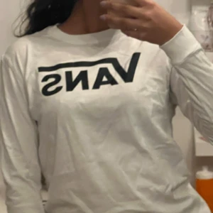 Vit långärmad tröja från Vans - Säljer en vit långärmad tröja från Vans med deras ikoniska logga i svart på framsidan. Perfekt för en avslappnad stil och passar bra till jeans eller shorts. Tröjan är i en bekväm passform och gjord av mjukt material.