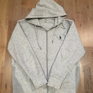 Grå hoodie från Polo Ralph Lauren - Säljer en stilren grå hoodie från Polo Ralph Lauren med dragkedja och huva. Storleken är S och passar runt 175cm. Priset är diskuterbart🙌