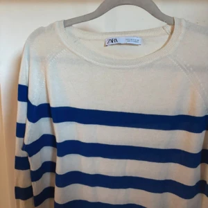 Randig tröja från Zara - Säljer en snygg randig tröja från Zara i ungefär creme vit  och blått. Tröjan har långa ärmar och en rund halsringning. Perfekt för en avslappnad stil. Även tun i materialet 