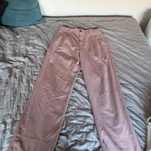 Rosa chinos/kostymbyxa - Snygga rosa chinos med en klassisk design. Byxorna har en rak passform och stängs med knappar. Perfekta för en stilren look.