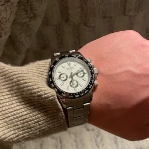 Panda Seiko Mod - Tvär snygg och stilren klocka från Seiko med silverfärgad länk och vit urtavla. Som efterliknar den kända modellen ”Panda” .40 mm. Klockan har tre sub-dials och en svart bezel med vita markeringar. Perfekt för den som gillar en klassisk och tidlös design. Klockan är automatisk! Med en NH34 movement. Chronograph funktionen fungerar inte! Om ni har några frågor är det bara att ställa privat!