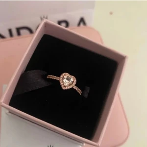 Ring med hjärtformad sten - Säljer en superfin ring med en glittrig hjärtformad sten i mitten. Ringen är i roséguld och har små gnistrande stenar runt om, Pandora liknade ring Perfekt för speciella tillfällen eller som en kärleksfull. Ringen kommer inte i box. 
