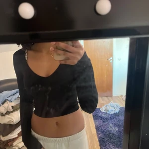 Svart croppad tröja från Bershka - Snygg svart croppad tröja från Bershka med v-ringning. Perfekt för en stilren look. Tröjan har långa ärmar och är gjord i ett mjukt material.