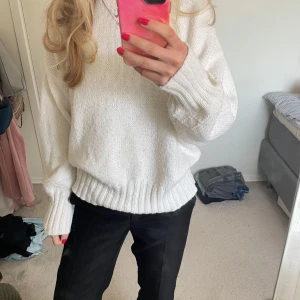 Vit stickad tröja - Mysig vit stickad tröja med långa ärmar och ribbade muddar. Perfekt för kyligare dagar och enkel att matcha med olika outfits. Detaljer på armarna.