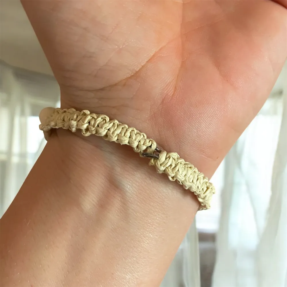 Snyggt set med armband och örhängen dekorerade med vita snäckor. Armbandet är knuten med makramé av pappersgarn på en wiretråd, med bruna träpärlor och snäckor. örhängena har en guldig blomformad detalj med hängande snäckor. En vacker kombo till din outfit!. Asusteet.