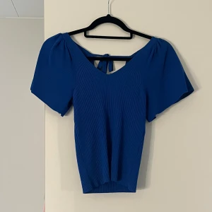 Blå topp - Snygg blå ribbad topp med korta ärmar och v-ringning. Toppen har en fin knytning i ryggen och är i storlek xs. Den är stretchig och sista bilden är för att se hur den ser ut på💕