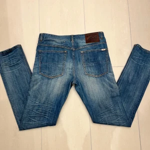 Jeans från Emmett - Galet feta blå jeans från Emmett med en vintage look och en bekväm passform. Byxorna har en lätt tvättad look med subtila slitningar och en läderpatch med logotyp på baksidan. Perfekta för en avslappnad stil, klassisk stil, fest klädsel 🙌🤙🍾