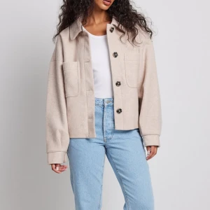 Beige overshirt från NA-KD - Snygg beige overshirt från NA-KD med stora knappar och två framfickor. Jackan har en klassisk krage och långa ärmar, perfekt för lager-på-lager-stil. Passar utmärkt till jeans för en avslappnad look. Skriv för bild på den jacka jag säljer .