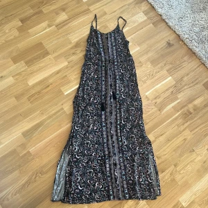 Mönstrad långklänning med smala axelband - Säljer en mönstrad långklänning med smala axelband. Klänningen har ett unikt mönster i olika färger och en luftig passform. Perfekt för en dag vid havet eller en sommarkväll. 🌊