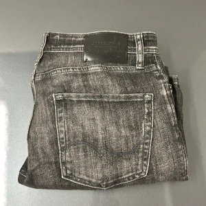 Svarta jeans med slitningar från Jack and Jones  - Snygga svarta jeans från Jack and Jones med en cool tvättad look. De har en tapered passform. Skick 9/10. Skriv vid frågor ✅