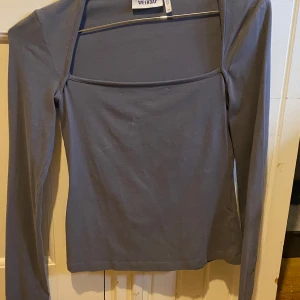 Grå långärmad topp från Weekday - Säljer en stilren grå långärmad topp från Weekday. Toppen har en fyrkantig halsringning och är i en mjuk och bekväm bomullsmix. Perfekt för lager-på-lager eller att bära som den är. Använd nån få gång