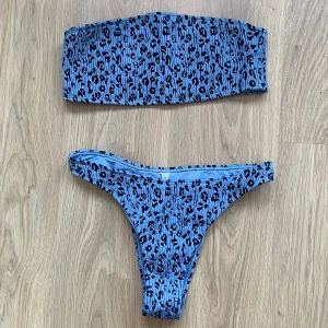 Blå leopardmönstrad bikini - Snygg blå bikini med leopardmönster. Överdelen är axelbandslös och underdelen har en klassisk trosa. Perfekt för en dag på stranden eller vid poolen.
