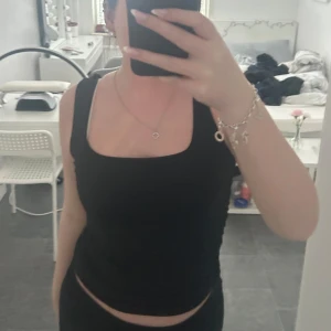 Svart linne/topp  - Säljer en jättenice svart linne/topp. Perfekt för varma dagar eller som ett tränings linne. Toppen har en enkel design med breda axelband  och en rundad halsringning. Toppen är ej använt bara testat.