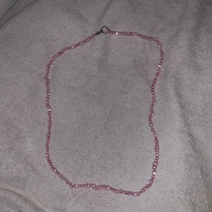 Rosa pärlhalsband. 1 gång använd  - Charmigt rosa pärlhalsband med små oregelbundna pärlor som ger en unik look. Halsbandet har ett enkelt lås i metall som gör det lätt att ta på och av. Perfekt för att lägga till en färgklick till din outfit.