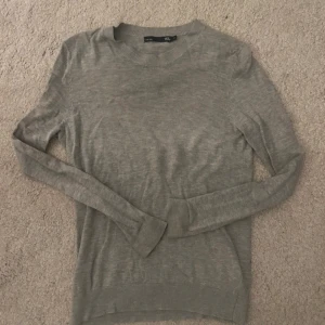 Grå tröja från 157 - Säljer en stilren grå tröja från 157 i storlek XS. Tröjan är långärmad och har en rund halsringning med ribbade kanter. Perfekt för en avslappnad look.