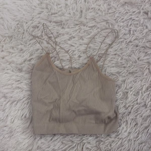 Beige ribbad linnetopp - Säljer en stilren beige ribbad linnetopp med tunna axelband. Perfekt för varma dagar eller som ett lager under en tröja. Enkel och snygg design som passar till det mesta.