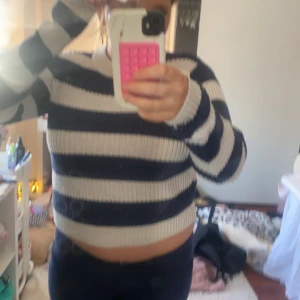 Randig stickad tröja - Säljer en mysig stickad tröja med breda ränder i marinblått och vitt. Tröjan har en croppad passform och långa ärmar, perfekt för en avslappnad stil. Den är ribbad vilket ger en fin struktur och extra komfort.