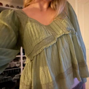Söt grön topp med spets - Säljer en söt grön blus med spetsdetaljer och puffiga ärmar. Blusen har en lös passform och är perfekt till sommaren. Armarna är lite kortare nästan treskvarts vilket är superskönt när det blir varmt. Den här en bred ringning och en lätt volang vid midjan.