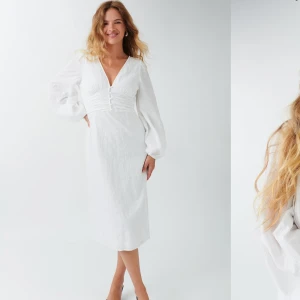 Vit klänning med v-ringning - Elegant vit klänning med v-ringning och långa ärmar. PERFEKT till STUDENT OCH SOMMAR! Klänningen har en smickrande rynkad detalj framtill och en slits baktill för extra rörelsefrihet. Slutsåld online. Nypris 599 kr! Använd 1 gång! 