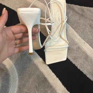 Vita klackskor med remmar - Eleganta vita klackskor med smala remmar och fyrkantig tå. Perfekta för en stilren look.