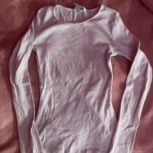 Vit ribbad långärmad topp - Säljer en vit ribbad topp med långa ärmar. Perfekt för lager-på-lager eller som den är. Stl XS