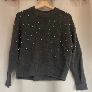 Grå tröja med pärlor - Säljer en jätte fin grå tröja dekorerad med små pärlor. Tröjan har långa ärmar och en rund halsringning, perfekt för kyligare dagar!! Den är både mysig och trendig, ett måste i garderoben! Pris kan diskuteras! Någon enstaka pärla kan sitta löst (inget som syns)❣️