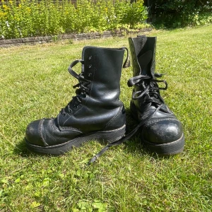 Gamla Svarta dr martens kängor - Säljer ett par robusta svarta dr martens kängor, tillverkade i England. De har en kraftig sula och snörning framtill. Väll använda men sulan är suprisingly inte så ner slipad. Men sulan i är väll använd. Storleken är oklar men skulle tro 37. Skorna är gjorde nån gång under 1995-2003