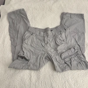 Grå cargobyxor - Snygga grå cargobyxor med flera fickor och elastisk midja.  Byxorna har en loose passform och är i storleken 38. Knappt använda, men de hade säkert blivit snyggare efter strykning!