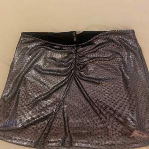 Snygg glittrig kjol från H&M Divided i silver. Kjolen har en tight passform och är kort, perfekt för en kväll ute. Den har en rynkad detalj framtill som ger en extra touch.