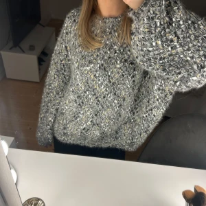 Mönstrig stickad tröja - Mysig stickad tröja med ett unikt mönster och inslag av gult. Perfekt för kyliga dagar med sin fluffiga och varma design. Tröjan har långa ärmar och en avslappnad passform.