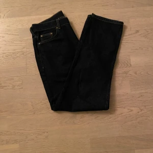 Mörkblå jeansbyxor - Snygga svarta jeansbyxor med klassisk femficksdesign och kontrasterande sömmar från Grunt. Perfekta för en stilren look. Har en baggy passform med storlek W28 men passar 30 och L32. Endast använda 1 gång. Pris kan diskuteras.