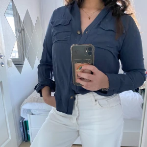 Mörkblå skjorta från Vero Moda - Snygg mörkblå skjorta från Vero Moda i storlek XS. Skjortan har långa ärmar och knappar framtill samt två bröstfickor. Perfekt för en stilren look.