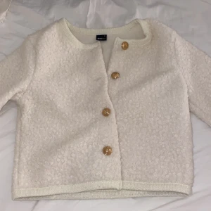 Vit teddyjacka/kofta med guldknappar - Mysig vit teddyjacka från Ginatricot med dekorativa guldknappar. Jackan har en , fluffig textur. Perfekt för kyliga dagar när du vill hålla dig varm och trendig. Nypris 499💕 säljs för 299 eftersom aldrig använd ❤️ pris kan diskuteras 