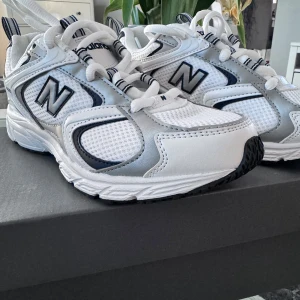 Vita sneakers från New Balance - Snygga vita New Balance 408 sneakers med svarta och grå detaljer. Skorna har en bekväm passform och är perfekta för vardagsbruk. De har en robust sula och klassisk snörning för en säker passform.