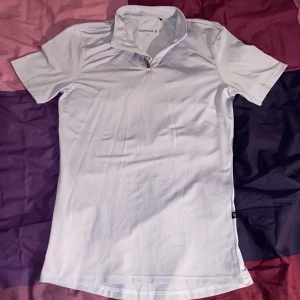 Ljuslila kortärmad ridtröja från Equipage - Säljer en ljuslila kortärmad ridtröja från Equipage. Tröjan har en dragkedja framtill och är tillverkad i ett stretchigt material av polyester och elastan. Perfekt för en aktiv livsstil.